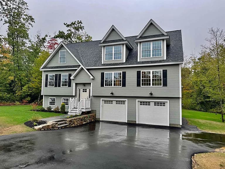 Custom-built Cape home exterior with dormers and two-car garage — new construction by J&M Contracting in Barrington, NH