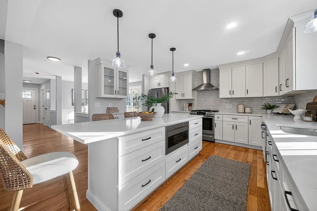 Custom kitchen with large center island, pendant lighting, and stainless appliances